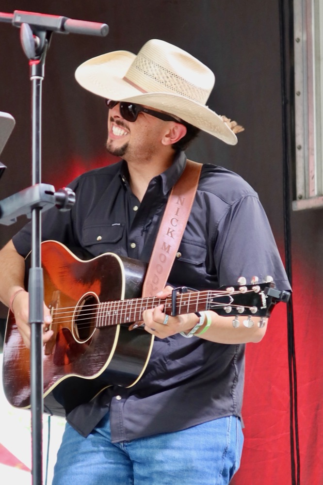 Nick Moody singing and playing guitar in a straw hat